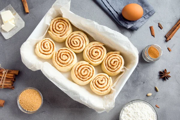 Rulo tarçın veya cinnabon, gri taş zemin üzerine pasta malzemeler ile ev yapımı tarifi çiğ hamur hazırlık şekerli geleneksel tatlı buns.