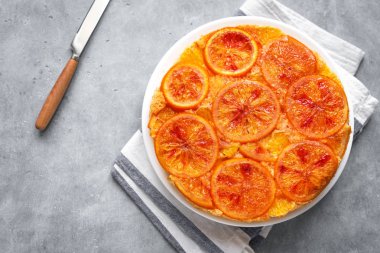 Gri arka plan, üstten görünüm üzerinde baş aşağı turuncu kek. Ev yapımı kek ile kanlı portakal, narenciye.