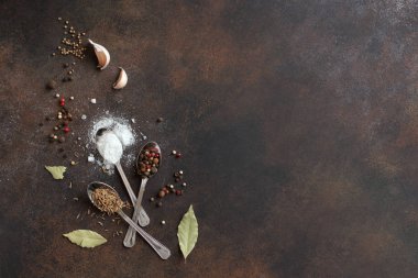 Arka plan baharat ve karanlık rustik masa, üstten görünüm, kopya alanı deniz tuzu ile yemek yiyecek. Çeşitli biber, sarımsak, defne yaprağı, kimyon, kişniş, tuz - baharat ürün çeşitliliği.