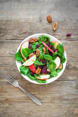 Ispanak, pekan fındık ve kuru cranberries ahşap arka plan, üstten görünüm üzerinde elma salatası. Heathy temiz vejetaryen çiğ gıda, taze salata.
