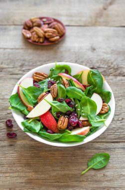 Ispanak, pekan fındık ve kızılcık ahşap arka plan, kopya alanı üzerinde elma salatası. Heathy temiz vejetaryen çiğ gıda, taze salata.