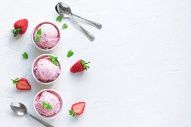 Çilekli dondurma ve beyaz arka planda, üstten görünüm taze çilek. Üç kâse çilekli dondurma, sağlıklı tatlı yaz.