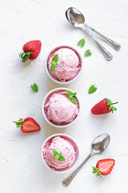 Çilekli dondurma ve beyaz arka planda, üstten görünüm taze çilek. Üç kâse çilekli dondurma, sağlıklı tatlı yaz.