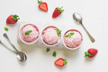 Çilekli dondurma ve beyaz arka planda, üstten görünüm taze çilek. Üç kâse çilekli dondurma, sağlıklı tatlı yaz.