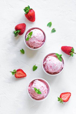 Çilekli dondurma ve beyaz arka planda, üstten görünüm taze çilek. Üç kâse çilekli dondurma, sağlıklı tatlı yaz.