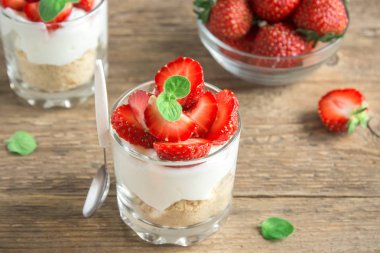 Çilekli tatlı krem peynir ve ahşap zemin üzerine taze çilek ile. Gözlük sağlıklı ev yapımı çilekli cheesecake.
