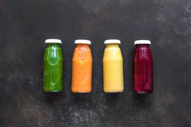Çeşitli tatlılar veya suyu şişelerde, sağlıklı diyet Detoks vegan temiz gıda kavramı, üstten görünüm alanı kopyalayın. Koyu arka plan üzerinde renkli smoothies.