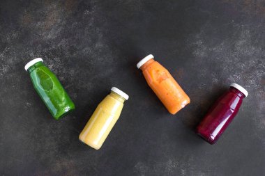Çeşitli tatlılar veya suyu şişelerde, sağlıklı diyet Detoks vegan temiz gıda kavramı, üstten görünüm alanı kopyalayın. Koyu arka plan üzerinde renkli smoothies.