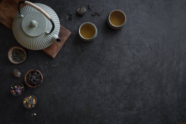 Çeşitli çay seçimi, çaydanlık ve Teacups siyah arka plan, kopya alanı üzerine. Geleneksel Asya çay aranjman - demir demlik ve çay ile seramik çay bardaklarından.