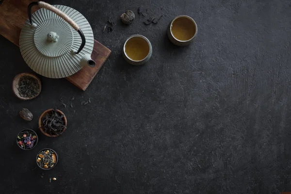 Çeşitli çay seçimi, çaydanlık ve Teacups siyah arka plan, kopya alanı üzerine. Geleneksel Asya çay aranjman - demir demlik ve çay ile seramik çay bardaklarından.