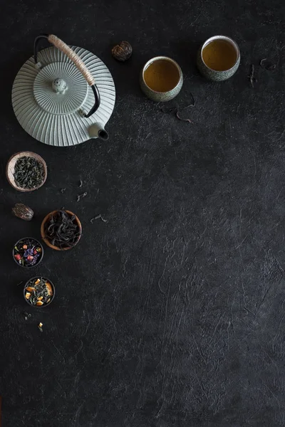 Çeşitli çay seçimi, çaydanlık ve Teacups siyah arka plan, kopya alanı üzerine. Geleneksel Asya çay aranjman - demir demlik ve çay ile seramik çay bardaklarından.