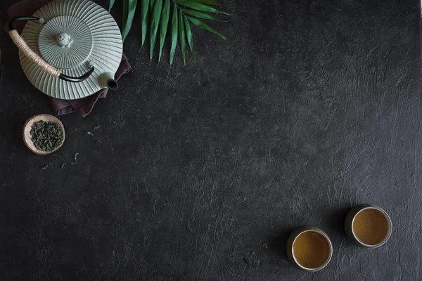 Çaydanlık ve Teacups siyah arka plan, kopya alanı üzerine. Çay töreni - demir demlik ve çay, üstten görünüm ile seramik çay bardaklarından için geleneksel Asya düzenleme.