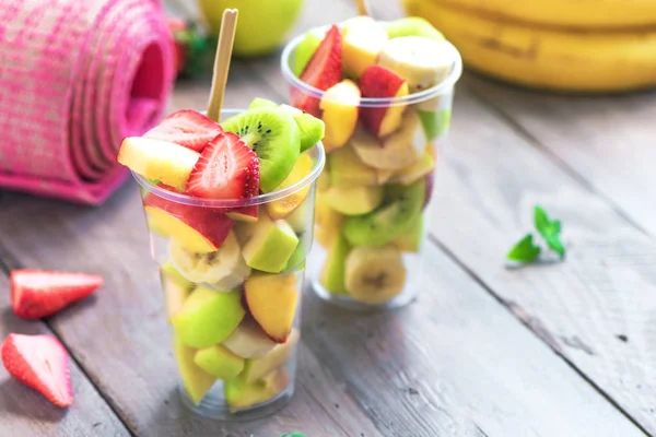 Spor ve sağlıklı yaşam konsepti. Pink Yoga mat ve meyve ve çilek git, uzay, üstten görünüm kopyalamak için salata plastik kap içinde.