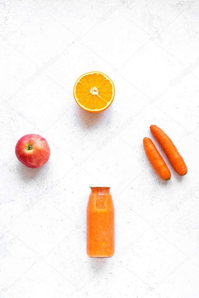 Carrot, apple and orange smoothie bottle and ingredients on white background, copy space, top view. Making detox diet vegan healthy smoothie or juice.