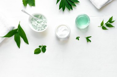 Doğal ekolojik güzellik tedavisi. Kozmetik ürünler, havlu ve yeşil yapraklar beyaz arka planda, üst manzara, kopyalama alanı. Doğal organik cilt bakımı, spa, sağlıklı yaşam tarzı konsepti..