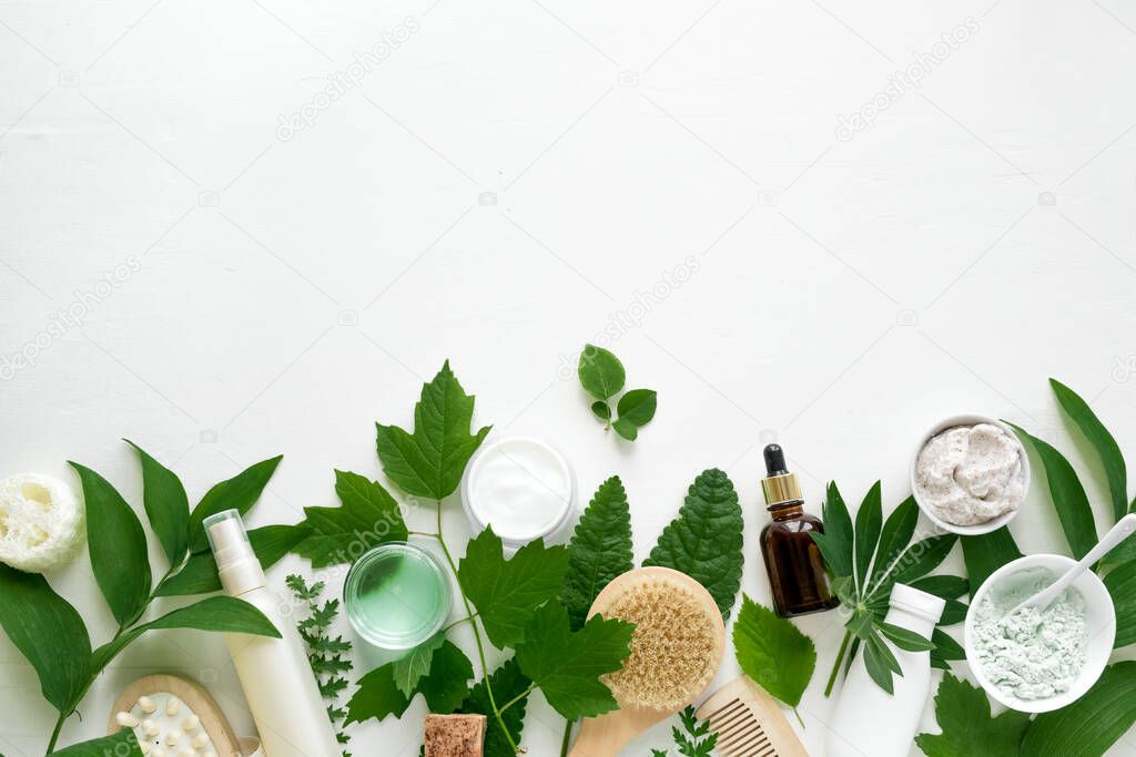 Natural eco beauty. Cosmetic products and green leaves on white background, top view, copy space. Natural organic skincare, spa, healthy lifestyle concept.