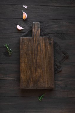 Siyah ahşap mutfak masasında boş tahta kesme tahtası, üst manzara, düz yatış. Tahta tabaklar..
