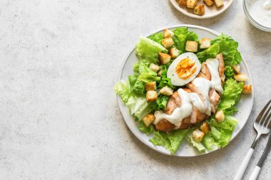 Beyaz arka planda tavuk göğsü olan Sezar salatası, üst manzara, kopyalama alanı. Sağlıklı öğle yemeği için taze tavuk salatası..