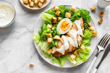 Sezar salatası, tavuk göğsü, mermer arka plan, üst manzara, yakın çekim. Sağlıklı öğle yemeği için taze tavuk salatası..