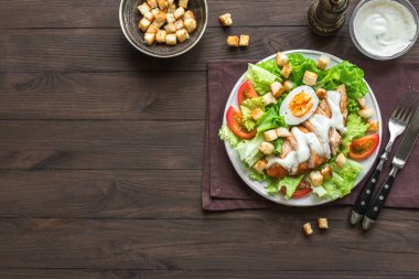 Koyu ahşap arka planda tavuk göğsü olan Sezar salatası, üst manzara, kopyalama alanı. Sağlıklı öğle yemeği için taze tavuk salatası..