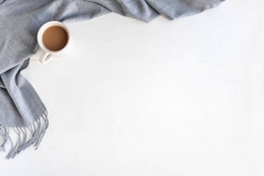 Sıcak gri eşarp veya battaniye ve beyaz arka planda bir fincan sıcak kahve, üst manzara, fotokopi alanı. Mevsimlik konsept.