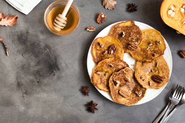Cevizli ve ballı balkabağı krepleri taş masada, üst manzara, kopyalama alanı. Geleneksel sonbahar sağlıklı kahvaltısı - balkabağı pankekleri.