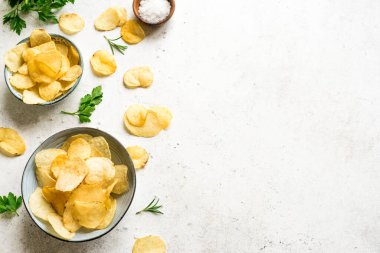 Kâselerde ev yapımı patates cipsi. Beyaz arka planda fırında patates cipsi, üst manzara, kopyalama alanı..