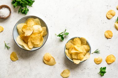 Kâselerde ev yapımı patates cipsi. Beyaz arka planda fırında patates cipsi, üst manzara, kopyalama alanı..