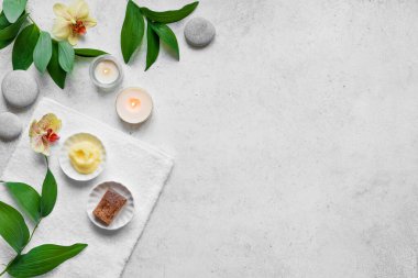 Beyaz taş zemin üzerine spa konsepti, tropikal yapraklar, çiçekler, mumlar, gri taşlar gibi zen, üst görünüm, kopyalama alanı. Rahatlama zamanı, spa ritüeli..