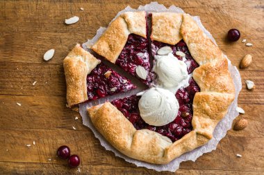 Bademli Cherry Galette ve ahşap üzerinde vanilyalı dondurma, üst manzara, kopyalama alanı. Ev yapımı sağlıklı tatlı - vişneli turta ya da Fransız galeti.