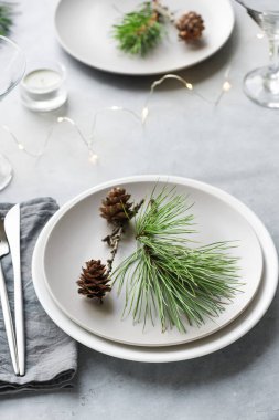 Açık gri masa üzerinde çam dalları ve koni ile Noel Masası, kopyalama alanı. Noel yemeği, parti tasarımı, konsept.