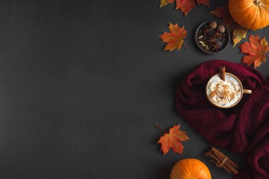 Sonbahar kompozisyonu - Balkabağı Baharatlı Latte, ılık eşarp, siyah arka planda sonbahar akçaağaç yaprakları ve balkabağı, yaratıcı düzlük, üst manzara, kopyalama alanı. Kahve içilen mevsimlik sonbahar konsepti.