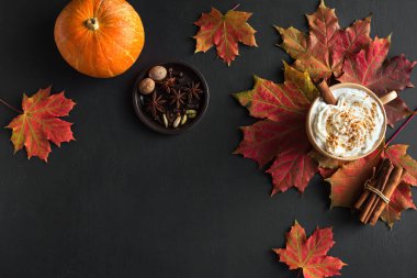 Sonbahar kompozisyonu - Balkabağı Baharatlı Latte, sonbahar akçaağaç yaprakları ve siyah zemin üzerinde balkabağı, yaratıcı düz döşeme, üst manzara, kopyalama alanı. Kahve içilen mevsimlik sonbahar konsepti.