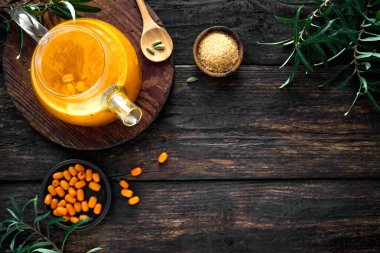 Kırsal ahşap arka planda cam çaydanlıkta deniz dikenli üzümlü çay, üst manzara, kopyalama alanı. Mevsimlik sonbahar baharatlı deniz dikenli çay.