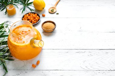 Beyaz ahşap masanın üzerinde cam çaydanlıkta deniz dikenli üzümlü çay. Mevsimlik sonbahar baharatlı deniz dikenli çay ya da punç.