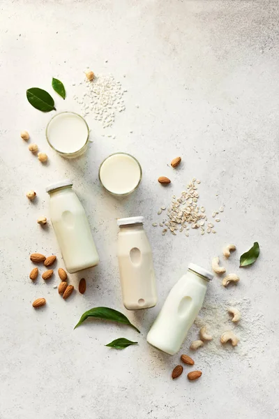 Various vegan plant based milk and ingredients, top view, copy space. Dairy free, lactose free nut and grains milk, substitute drink, healthy eating.