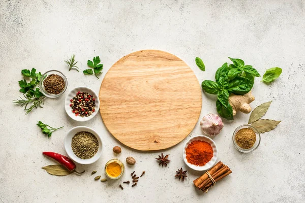 Various Spices, Herbs and Condiments around plate on white stone table, top view, copy space. Healthy cooking, indian food background.