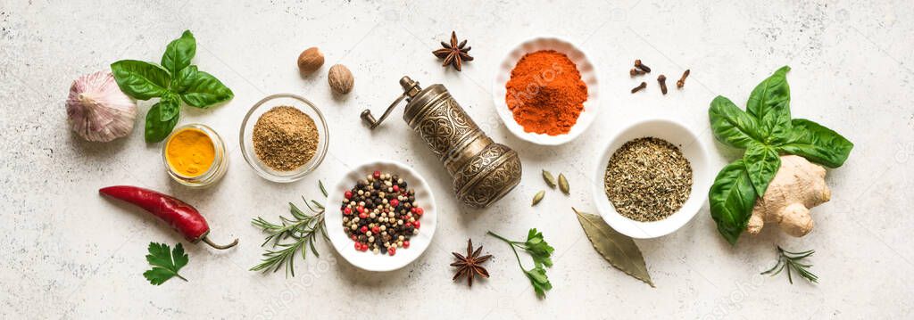 Various Spices, Herbs and Condiments around plate on white stone table, top view, banner. Healthy cooking, indian food background.