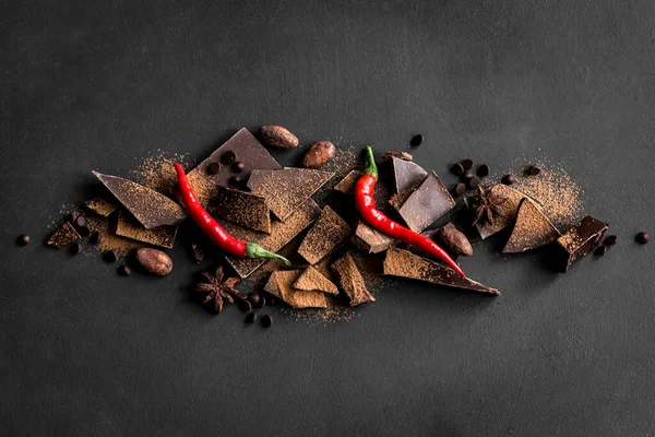 Kara Çikolata Arkaplanı. Çikolata parçaları, kakao tozu, acı biber ve baharatlar siyah masada, üst manzara, kopyalama alanı.