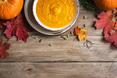 Balkabağı çorbası ve ahşap masada organik balkabakları, üst manzara, kopyalama alanı. Mevsimlik sonbahar yemekleri - Baharatlı balkabağı ve havuç çorbası.