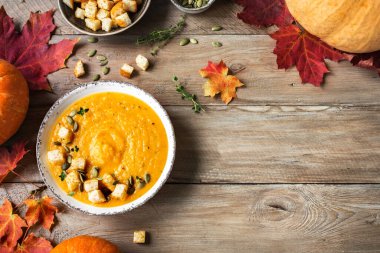 Balkabağı çorbası ve ahşap masada organik balkabakları, üst manzara, kopyalama alanı. Mevsimlik sonbahar yemekleri - Baharatlı balkabağı ve havuç çorbası.