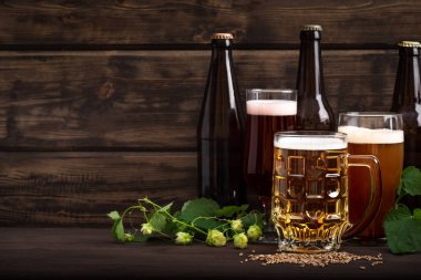 Şişelerde çeşitli bira fıçıları, bardaklar ve kupalar ahşap masa üzerinde, fotokopi alanı. Zıpzıp ve maltlı taze bira..