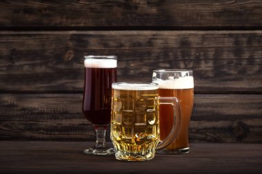 Bardaklarda çeşitli bira fıçıları ve ahşap masada kupalar, fotokopi alanı. Taze bira..