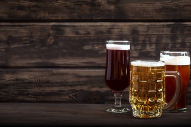 Bardaklarda çeşitli bira fıçıları ve ahşap masada kupalar, fotokopi alanı. Taze bira..