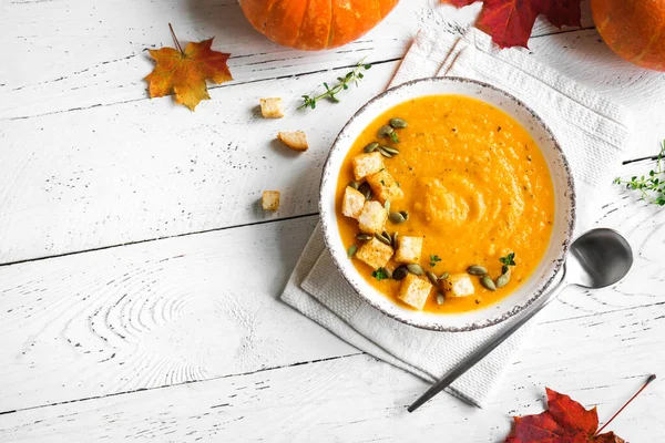 Kabak çorbası, kızarmış balkabağı tohumu, beyaz ahşap masa, üst manzara, fotokopi alanı. Mevsimlik sonbahar yemekleri - Baharatlı balkabağı ve havuç çorbası.