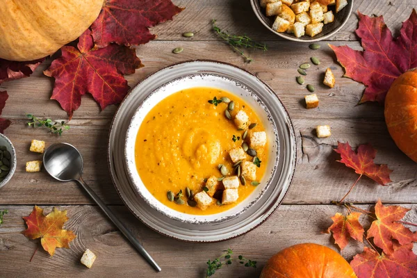 Balkabağı çorbası ve ahşap masada organik balkabakları, üst manzara, kopyalama alanı. Mevsimlik sonbahar yemekleri - Baharatlı balkabağı ve havuç çorbası.
