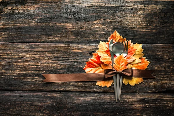 Autumn Thanksgiving Table Setting. Cutlery and autumn leaves on wooden table, autumn decor, copy space. Thanksgiving holiday menu concept.