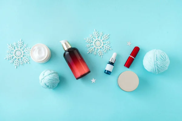 Winter Skin Care products and snowflakes on blue background, flat lay, copy space.  Seasonal beauty routine and skin protective cosmetic for winter weather concept.