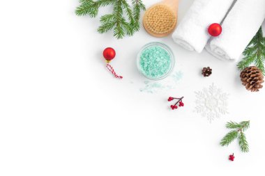 Noel Spa Konsepti ve Kış Cilt Bakımı ürünleri, beyaz arka planda köknar dalları ve kar taneleri, düz döşeme, kopyalama alanı. Mevsimlik güzellik rutini ve vücut bakımı kavramı.