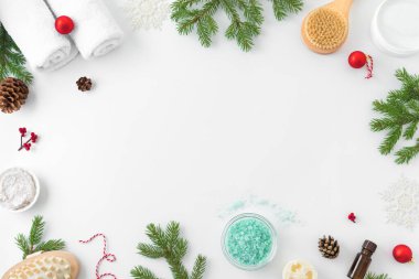 Noel Spa Konsepti ve Kış Cilt Bakımı ürünleri, beyaz arka planda köknar dalları ve kar taneleri, düz döşeme, kopyalama alanı. Mevsimlik güzellik rutini ve vücut bakımı kavramı.